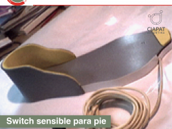 En la imagen se ve una base de madera, con una forma específica para adaptarse a un calzado, y de esta manera funcionar para manejar dispositivos digitales.
